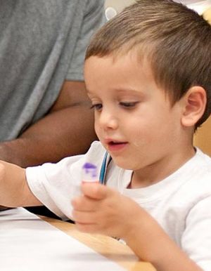 A young child uses creative supplies in a classroom